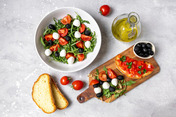 Mediterranean diets food. Mozzarella salad with tomatoes black olives arugula and olive oil. dish of Italian Greek cuisine. Healthy eating