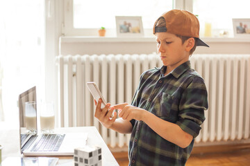 Angry boy reading a text message on smart phone at home.