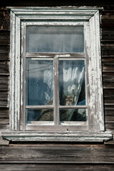Fototapeta na wymiar Alarmed cat sitting on a windowsill and looking out the window in an old country house.
