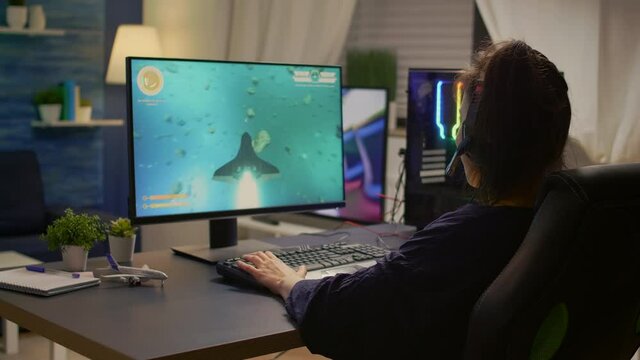 Pro gamer talking into microphone with other gamers during digital championship. Player wearing headphones and playing online video games with new graphics on powerful computer from gaming room