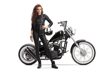 Obraz na płótnie Canvas Female biker holding a helmet and posing with a chopper motorbike