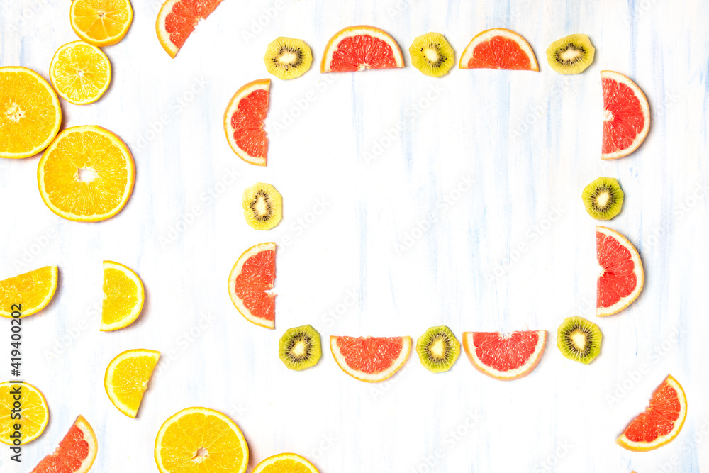 Poster top view of a frame with grapefruit and kiwi slices and orange slices on the white-blue background