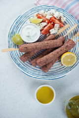 Raw fresh meat kofta or kefta on a blue and white plate, above view on a white stone background, vertical shot
