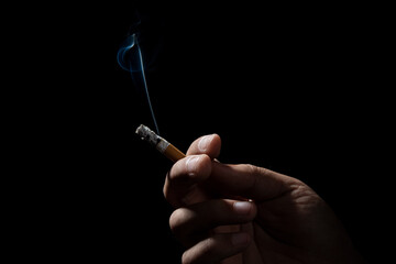 A Cropped of man hand holding cigarette black background