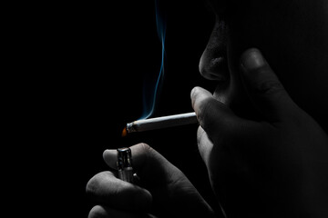 Close up young man smoking a cigarette black background