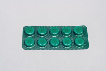 Medicines, pills in green blister pack on white background. Treatment of nfluenza, common cold,...