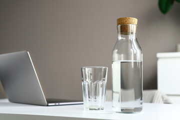 A glass water bottle and a glass on the table. Sunlight from the window. Healthy Lifestyle Concept