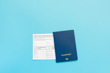 Vaccination card, passport, a vial with covid-19 vaccine. syringe and mask on a blue background,...