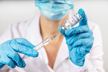 Vial withCOVID-19 vaccine and a syringe with a needle for injections for coronavirus infection in the hand of a doctor in a nitrile glove on a white background. Close-up. Concept fighting Coronavirus