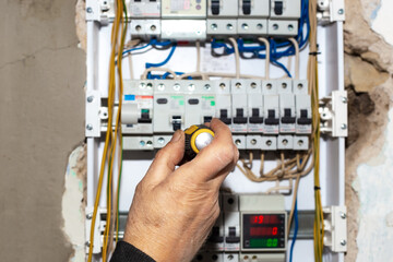 Electrical switchboard. A male electrician installs a multifunctional shield to control electricity into the wall of the house