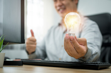 Businessman holding lightbulb and feeling delighted and excited by new innovation and ideas for...