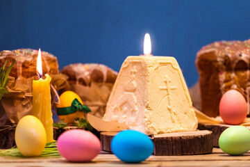 Orthodox Easter. The cakes and painted eggs, the curd mass and the burning candle in the background.