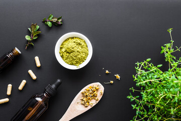 Natürliche Kräuter in Tabletten und Pulverform. auf einem schwarzen Hintergrund. Flat lay, Thymian, Löffel.