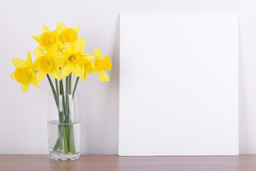 Breakfast still life., empty picture frame mockup on wooden desk, table. Vase with daffodils branches. Elegant working space, home office concept. Scandinavian interior design