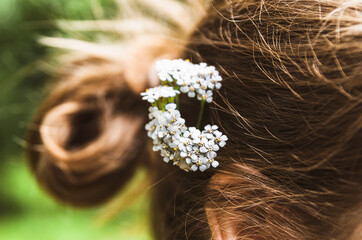 Małe białe kwiaty wplecione we włosy kobiety.