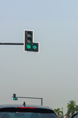 Green traffic lights on road with sky background.