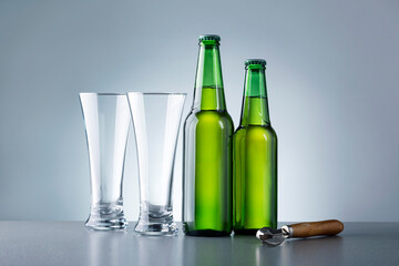 Two Glass And Bottles Of Beer Against Grey Background. Non alcoholic beverages.