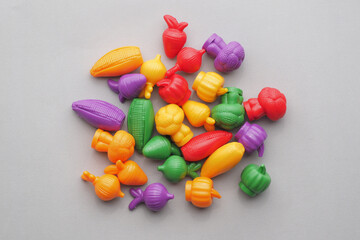 Colorful Plastic Vegetables on gray background.