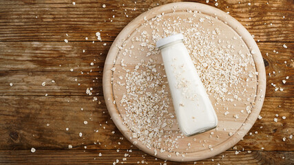 Oat flakes and bottle of fresh milk on a wooden board