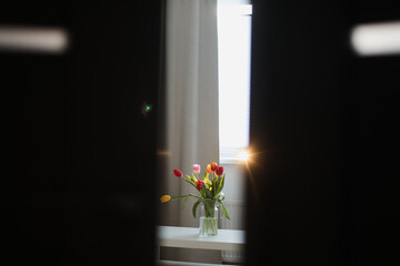 view behind the doors of a bunch of tulips in vase on a table in a living room