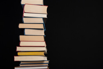 Pile of books stacked on a black background with space for copy