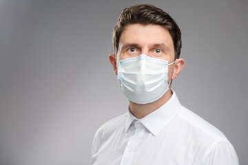 Man in a protective face mask, an office worker in white shirt wearing a mask to protect against covid-19. Businessman portrait on pandemic time.