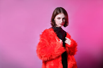 red-haired young girl in red fur coat clothes. pink background