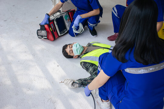 Team work medical emergency use Automated External Defibrillator (AED) being operated on during help unconscious worker accident in construction site.
