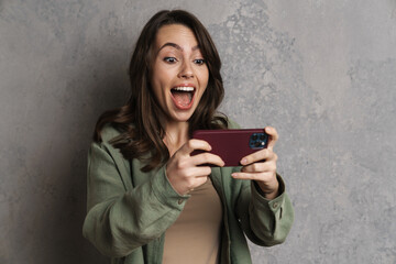 Fototapeta premium Delighted charming girl playing online game on mobile phone
