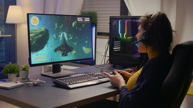 Competitive cyber gamer winning online video game tournament wearing professional headset. Pro player using joypad for space shooter championship sitting on gaming chair late at night in living room