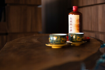 Fototapeta na wymiar Two oriental cups with a bottle of alcoholic drink in the background