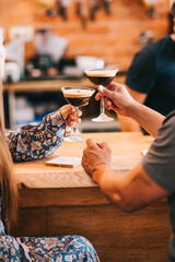 couple holding glass with espresso martini cocktail, decorated with coffee bean.
