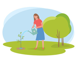 Young woman is watering a small tree from a watering can.