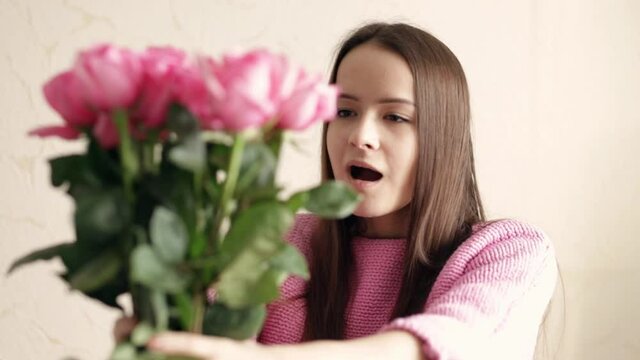 A young girl receives a bouquet of flowers, congratulations for the holiday on her birthday, spring roses as a gift