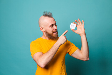 Bearded european man in yellow shirt isolated on turquoise background holding yes with surprise and...