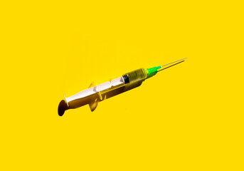 Syringe on yellow background. Concept of vaccination and protection against Covid-19