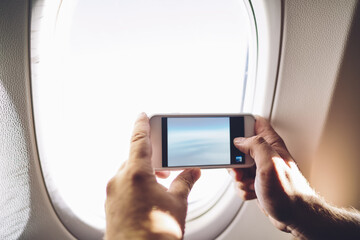 Man taking photo on smartphone in plane