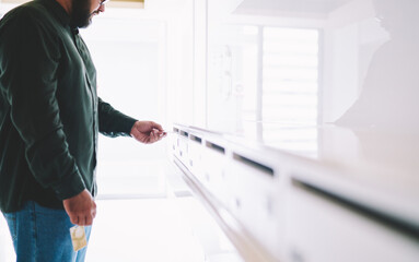 Man inserting business card in postal box in modern apartment building