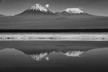 Obraz premium Black and white view of volcanoes across a salt lake in the Atacama Desert, Chile.