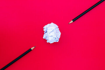 White paper ball with a black pencil on a red background.