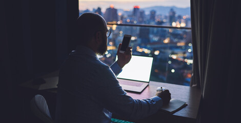 Businessman with smartphone in office at night