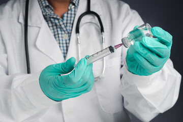 A doctor holding a syringe and COVID-19 vaccine bottle. Vaccine for immunization, and treatment from coronavirus infection. Front view. Concept of medical and the fight against coronavirus