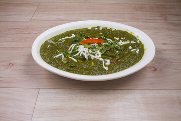 Palakpaneer or Spinach and Cottage Cheese curry, mortar with spices on dark background. Traditional Indian dish. Top view, copy space
