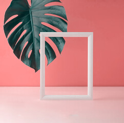 Empty white frame standing in an empty room decorated with tropical leaf.