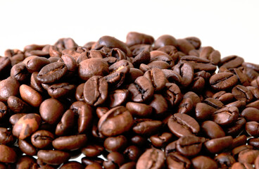 medium brown fresh roasted coffee bean pile closeup in selective focus. food and beverages concept. coffee ingredient. white background. copy space. 