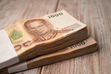 Stack of Thai baht banknotes on wooden background, business saving finance investment concept.