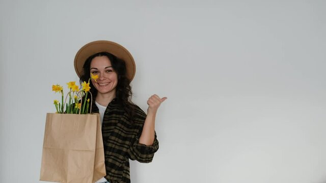 Female florist in shirt and hat with flower paper bag on white background