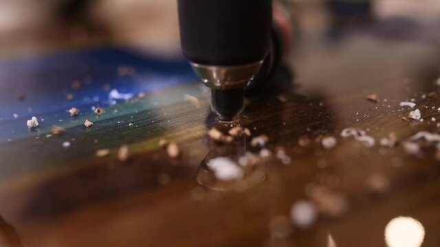 process of drilling holes in a new epoxy wood table