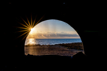 view of a beautiful sunrise over the ocean through the window of a pop up roof in a camper van