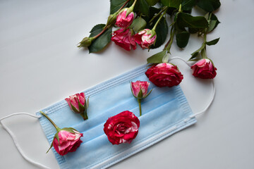 Pink rosebuds on the medical face mask and beautiful spring bouquet of spring flowers. 